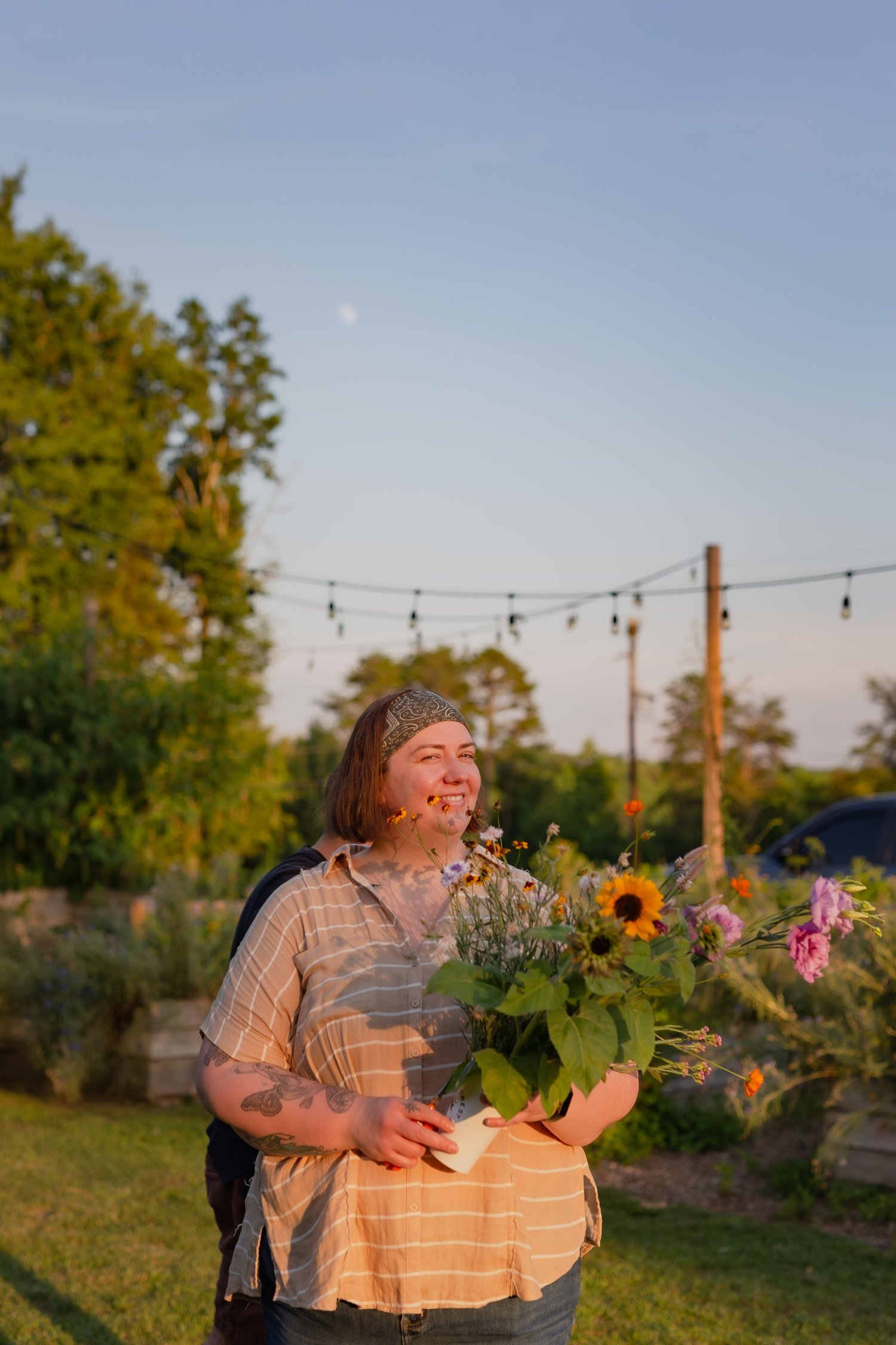A guest holding an armful of sunflowers and zinnias